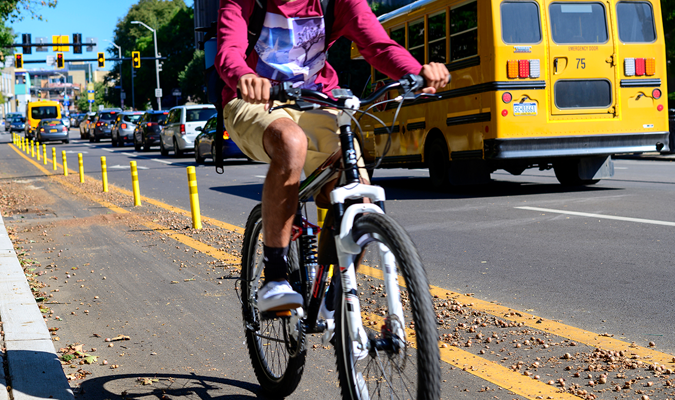 A child riding a bike with a school bus nearby